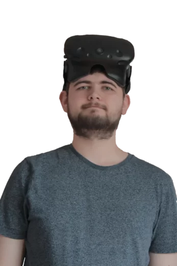 A man with a neutral expression wearing a grey t-shirt and a virtual reality (VR) headset positioned on his head like a hat.